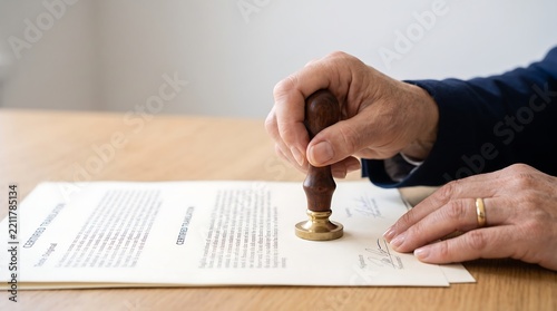 Person stamping and signing a certified translation document on a wooden desk