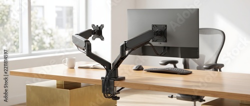 Dual monitor arm mount installed on wooden office desk with computer screen.