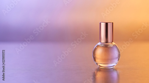 Glass perfume bottle on a gradient purple and orange background