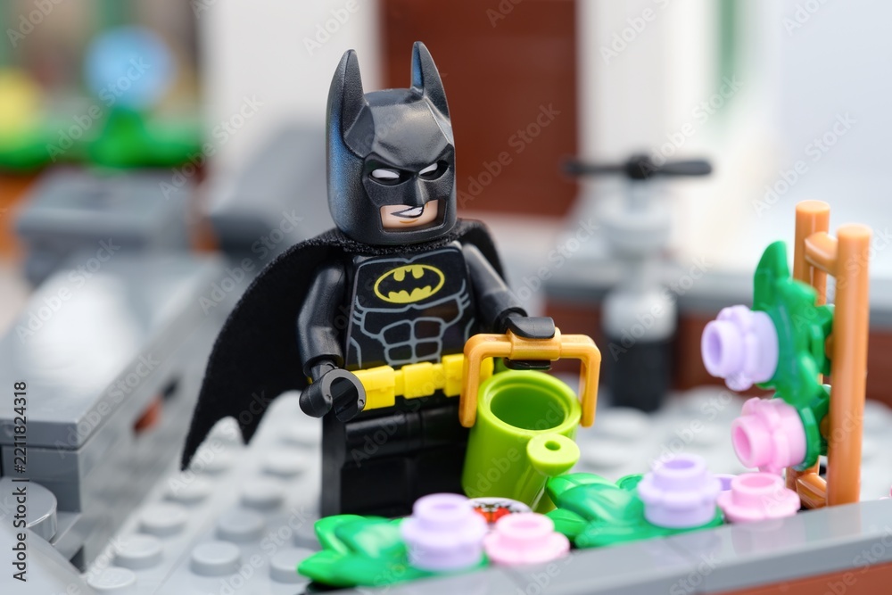 Obraz premium Tambov, Russian Federation - August 23, 2026 Lego Batman minifigure with a watering can next to a flower bed on a rooftop garden. Close-up