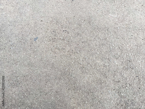 Fotografie Close-up of rough gray asphalt surface with fine gravel grains and subtle speckles, creating a coarse, weathered texture suitable for urban backgrounds and construction themes