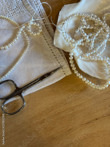 Natural freshwater pearls strands in seashell dish with scissors and lace napkin on wooden table for handmade jewelry making concept
