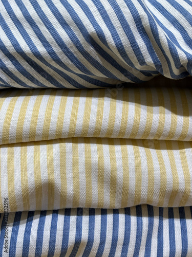 Folded yellow and blue striped cotton linen fabric stack for home textile and bedding background concept