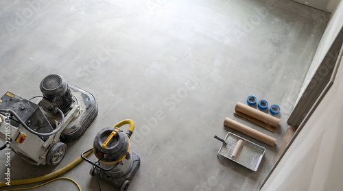 Professional preparation for epoxy floor coatings featuring heavy concrete grinding machine and painting tools