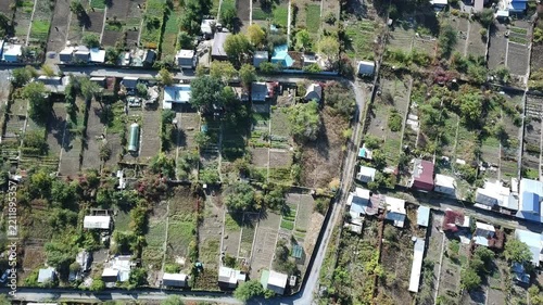 Aerial view of rural village with gardens and houses, top view of agricultural plots with roads