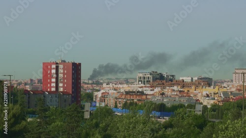 Black smoke column rising over a city skyline