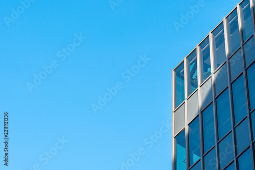 Modern corporate office building glass facade against a clear blue sky with ample copy space