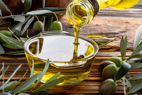 Organic olive oil pouring from carafe into glass bowl