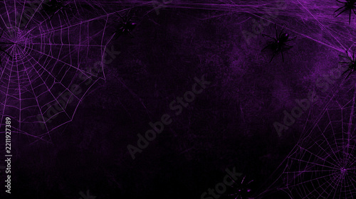 Spooky spider webs and spiders draped across a textured dark purple wall, haunted Halloween background concept, with copy space