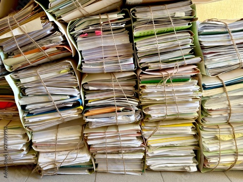 A close-up shot of heavy stacks of old, untidy paper documents, folders, and archives tightly bound together with twine, conveying bureaucracy and historical records