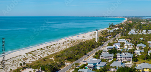 Expensive waterfront houses and white Boca Grande lighthouse on ocean shore. Small town on Gasparilla Island in southwest Florida. Premium housing development in the USA