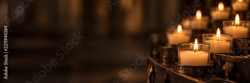 Pequeñas velas de iglesia encendidas dando luz tenue y cálida, y espacio negativo.