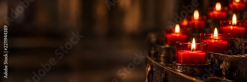 Pequeñas velas de iglesia encendidas dando luz tenue y cálida, y espacio negativo.