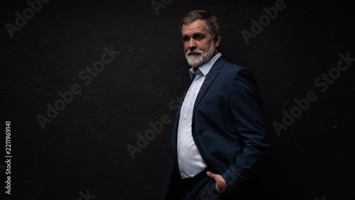 Studio portrait of senior businessman in suit on dark background