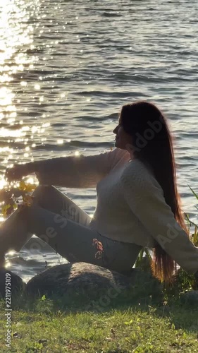 Silhouette Of Long Haired Woman Sitting On Lake Bank At Golden Hour Video