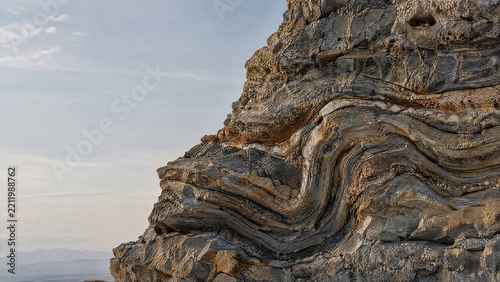 Folded rock strata texture on a layered cliff face in a mountain landscape  