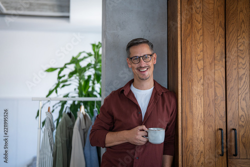 Smiling man holding coffee mug at home