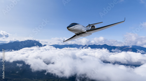 Luxury Private Jet Flying Above Clouds Over Mountain Landscape With Blue Sky and Scenic Views