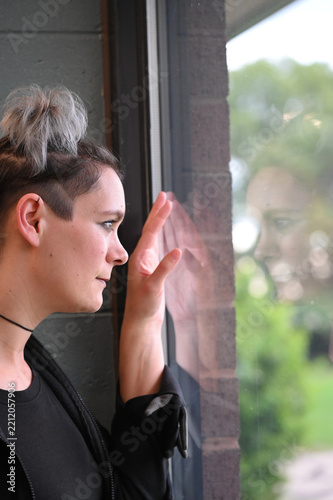 Thoughtful woman looking out window with reflection