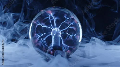 Blue Plasma Ball Emitting Electric Discharges Surrounded by Swirling Smoke and Thick Fog in Dark Studio Static Close Up