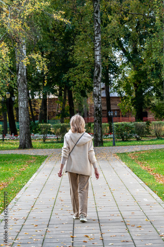 A woman walks along a paved path in the park.