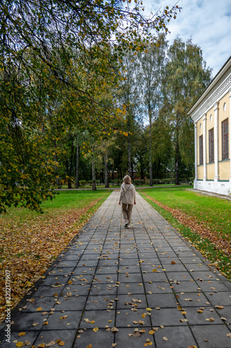 A woman walks along a paved path in the park.