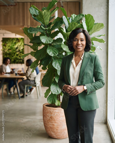 Smiling professional woman holding phone near plants