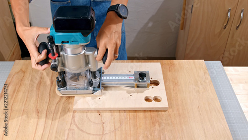 Obraz na plátně Man using an electric wood router to mill a circular hole in a