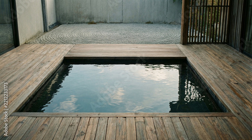 Japandi terrace featuring a minimalist flush wooden deck surrounding a square still water feature and zen garden