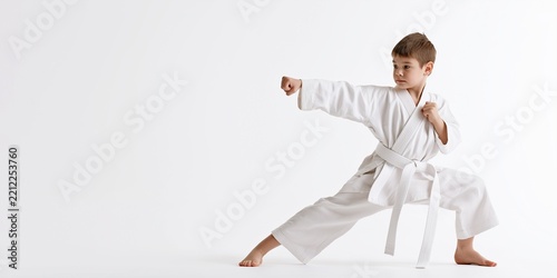 Karate little boy in action isolated on white background, martial arts kick