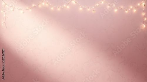 Soft pink wall decorated with string lights for cozy celebration