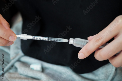 man is filling a clear liquid into a syringe for weight loss.concept of weight loss using pen techniques.