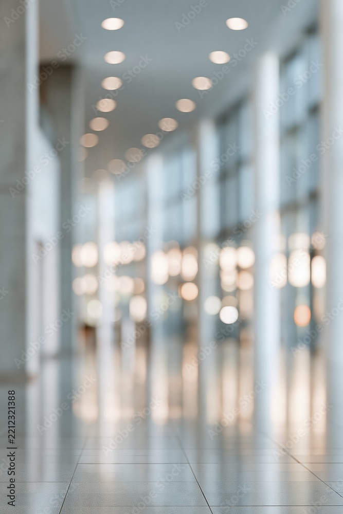 Naklejka premium Modern Office Hallway with Natural Light and Reflective Floor - Blurred Background