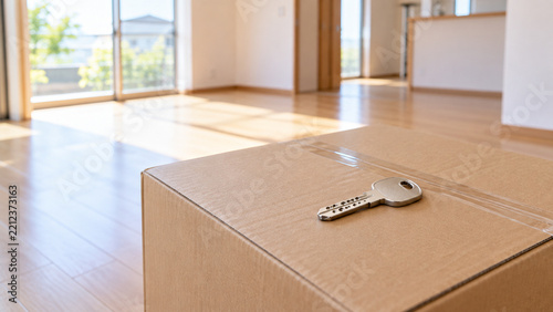 引っ越し用の段ボール箱の上に置かれた新しい鍵　空の新居のリビング