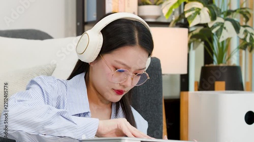 Asian Freelancer Woman Wearing Headphones and Working on Laptop at Home