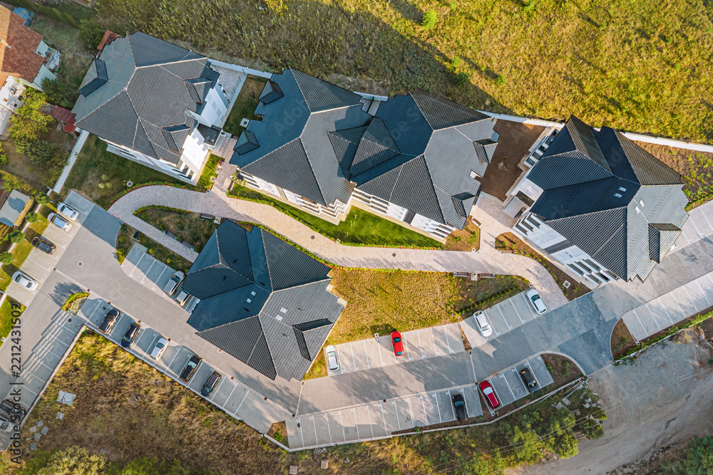 Obraz premium Drone view of a new suburban housing estate with winding roads and parking - ideal for real estate marketing and property development