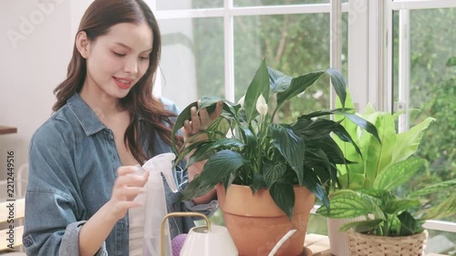 Happy young woman taking care of indoor plants at home.