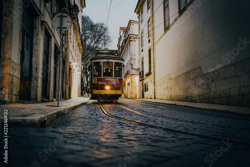 A colorful street scene in Lisbon showing a curved cobblestone road between.