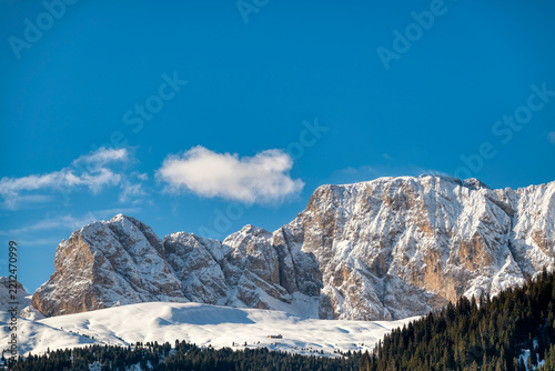 A majestic panorama of snow-capped Molignon mountain ridge in italian dolomites under a brilliant blue sky. Snow dusted peaks rise against the vast expanse of the sky. 