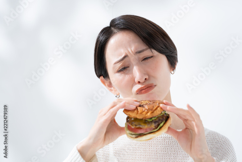 ハンバーガーを食べるか悩むダイエット中の女性