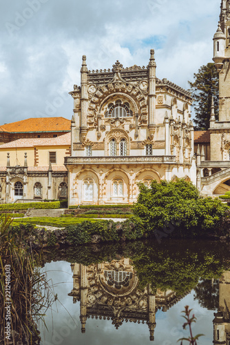 The magnificent Manueline architecture of Bussaco Palace reflected in a tranquil garden pond, Portugal