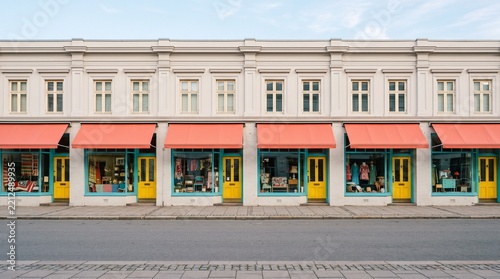 Elegant white storefront facade with coral awnings and colorful doors