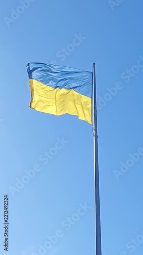 State flag of Ukraine waving on a flagpole against blue sky. Blue and yellow national banner waves in the wind, reflecting patriotism, freedom, independence and unity