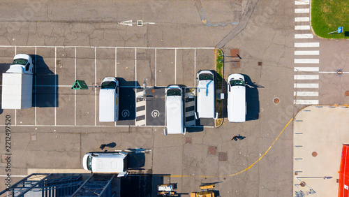 Aerial view of Plenitude On The Road Charging Station with white vans parked in a parking lot in San Giuliano Milanese, Lombardia, Italy.