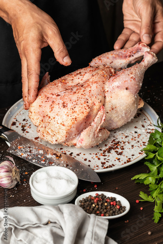 Chef rubs spices into a raw chicken carcass. Male hands, process of cooking baked chicken. Holiday food concept, recipe