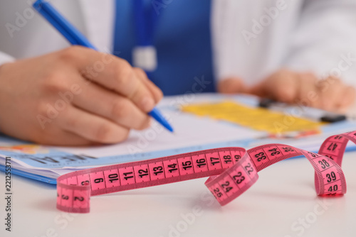 Weight loss and diet planning, doctor writing medical prescription with measu...