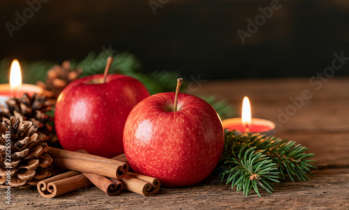 Elegant Christmas still life with red apples, cinnamon sticks, pine cones, fir branches and warm candleligh