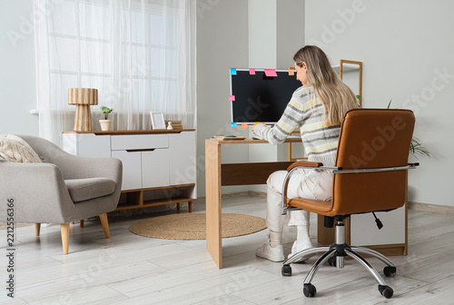 Remote work and burnout, woman working on computer at home with sticky notes ...