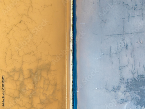 Aerial view of the salt ponds at Bedwell Bayfront Park, showing the contrast between orange and blue mineral-rich water basins separated by a levee in Menlo Park, California, United States.