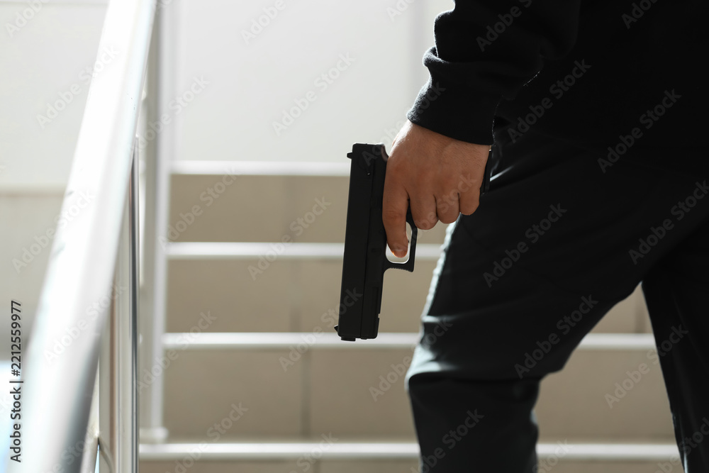 Obraz premium Crime and violence prevention person holding a handgun in a stairwell threat danger and public safety concerns in an urban environment